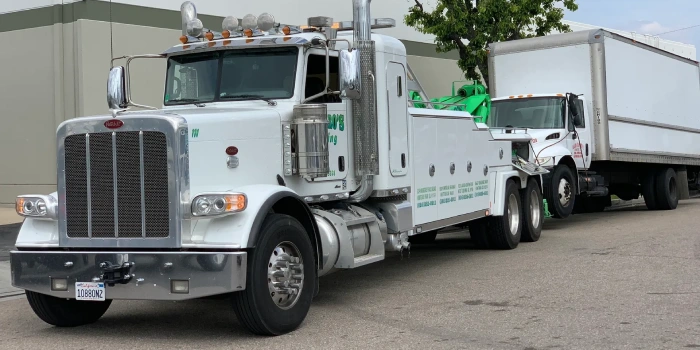 A white tow truck parked in front of a building.