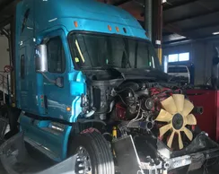 A blue truck with its front end broken down.