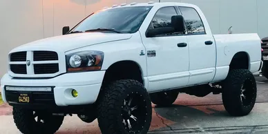A white truck with black rims parked in the street.