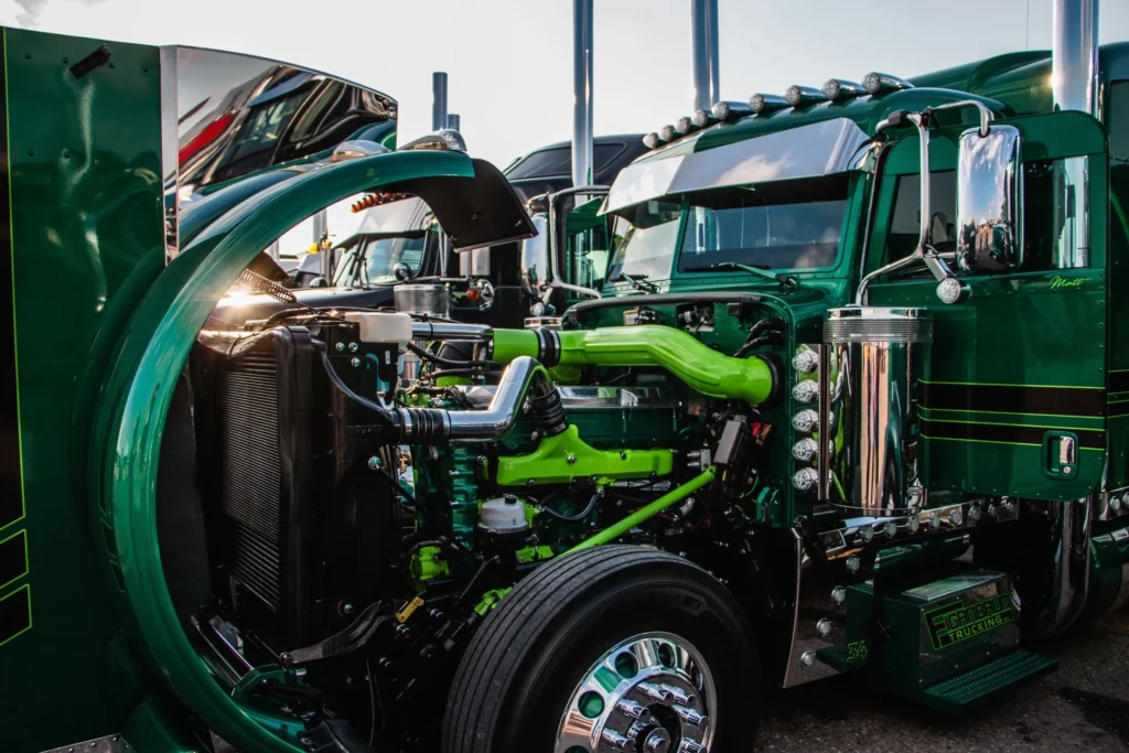 A green truck with its engine exposed.